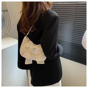 Detailed shot of white lace pearl crossbody bag with oversized silk bow and chain strap