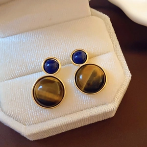Detail of vintage gold hoop earrings with brown tiger eye stone on white velvet box
