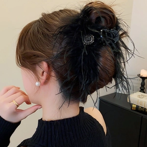 Détail d'une pince à cheveux luxueuse en plumes noires avec un strass carré étincelant