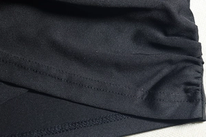 Detail of double-needle stitching and high-density black fabric texture on a slim mini dress