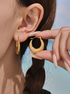 Detailed macro view of 18K gold hoop earrings featuring a unique fish scale texture
