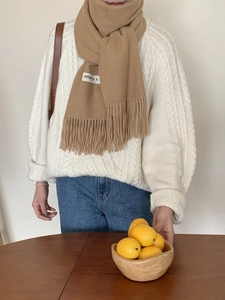 Detail of camel cashmere-feel scarf with tassel fringe and different woven label