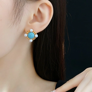 Detailed close-up of a vintage turquoise and pearl earring on a model's earlobe