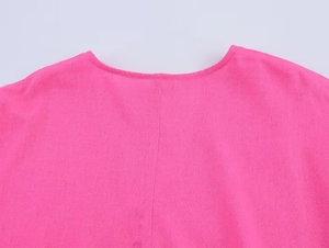 Vue macro du décolleté d'une chemise en lin rose pêche avec coutures et texture tissée