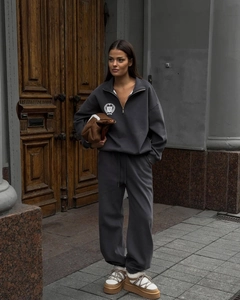 Détail de l'emblème de bouclier blanc sur un ensemble de sweat à demi-zip gris anthracite
