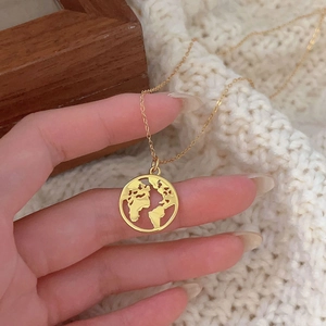 Macro shot of 925 sterling silver gold world map pendant necklace held in hand