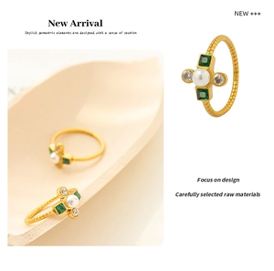 Detailed macro of gold ring featuring elegant pearl and green emerald zircon accents