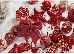 Macro view of red Christmas ornaments with glitter bows and stars on snowy surface
