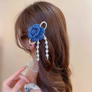 Detail of blue denim flower hair clip with pearl tassels and bow on model hair