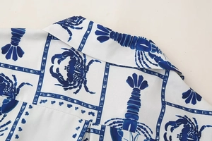 Close-up of white fabric shirt with blue lobster and crab prints on collar and shoulder
