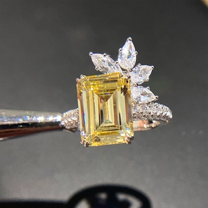 Macro shot of an emerald-cut yellow zircon ring with floral side stones and a diamond band