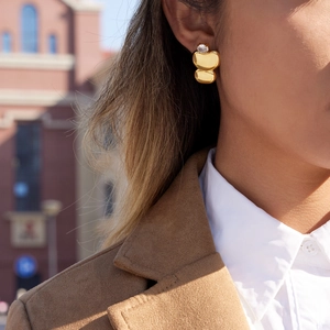 Detail of model wearing gold geometric egg-shaped earrings with round zircon inlay