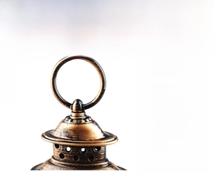 Close-up of vintage bronze lantern top with circular handle and metallic brushed finish