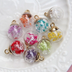 Close-up of glass orb pendants filled with colorful dried flowers and golden clasps