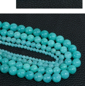 Macro shot of natural Amazonite round beads in various sizes on black leather texture