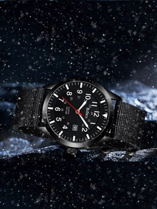 Close-up of military quartz watch with black nylon strap on snow-covered rocks