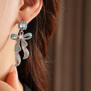 Détail macro de boucles d'oreilles nœud vintage avec perles turquoise et cristaux roses