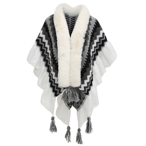 Detail of knitted poncho featuring faux fur collar and black-grey fringe accents