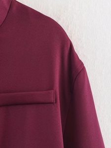 Detail der weinroten Bomberjacke mit gepolsterten Schulternähten und flacher Tasche