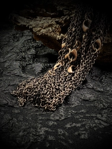 Close-up of vintage bronze chain necklaces with lobster clasps on textured dark fabric