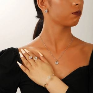 Detail shot of heart-shaped gold jewelry set with zircons worn by a model