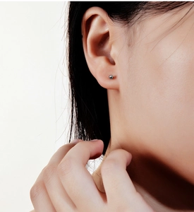 Close-up of a minimalist s925 sterling silver small ball stud earring on ear
