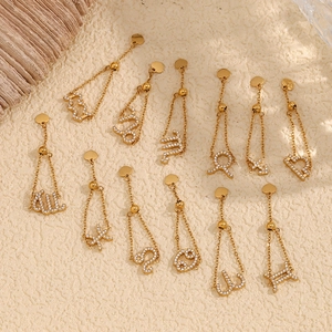 Vue à plat de boucles d'oreilles zodiaque en or 18 carats avec strass sur sable