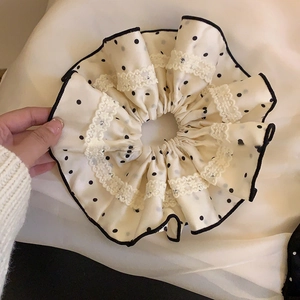 Detail showing beige satin polka dot scrunchie with delicate white lace edging