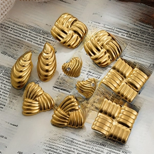 Flat lay of multiple 18k gold earrings with diverse geometric shapes on book pages