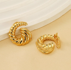 Detailed view of chunky gold croissant hoop earrings with a polished twisted rope design