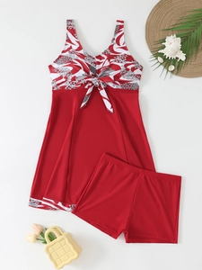 Flat lay of red and white floral tankini set with a skirt and swim shorts on white background