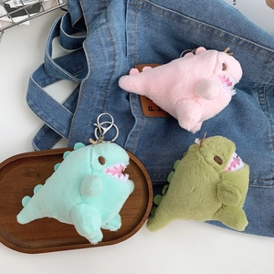 Detailed close-up of cute plush dinosaur keychain charms in pink and green colors