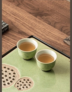 Close-up of green glazed ceramic tea cups on lotus pod pattern tray in zen aesthetic