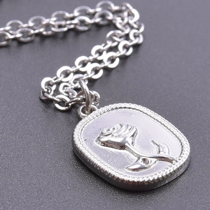 Macro shot of silver stainless steel oval pendant with 3D embossed rose flower detail