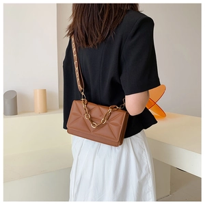 Brown small square bag with geometric embossing and golden chain detail on a model