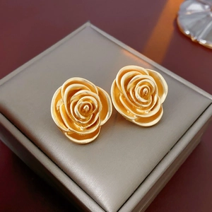 Detailed close-up of golden rose-shaped vintage stud earrings on a premium jewelry box