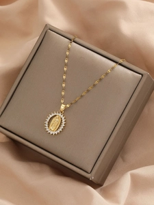 Close-up of golden Virgin Mary pendant with clear zircon inlay on a luxury jewelry box