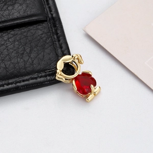 Detailed view of heart-shaped red zircon pendant with animal-shaped golden metal setting