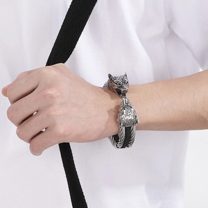 Macro detail of antique silver wolf head carving on a braided leather steel bracelet