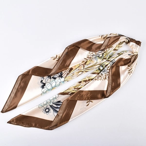 Detail of floral print satin scarf featuring brown borders and smooth silk-like texture