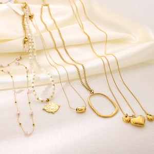 Chic gold-toned layered necklaces with heart and oval pendants on white silk fabric