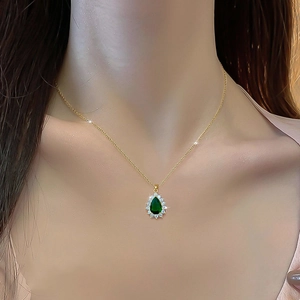 Elegant gold titanium necklace featuring a teardrop emerald pendant with micro-pave diamonds
