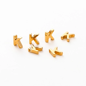 Detailed view of six gold vacuum plated 26-letter K charms for DIY jewelry making
