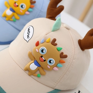 Detailed close-up of 3D cartoon monster and deer horn decoration on a beige baby baseball cap