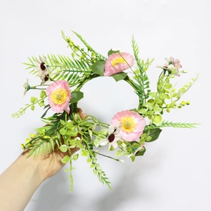 Close-up of artificial floral wreath with pink blossoms and green fern leaves