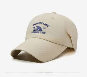 Close-up of a beige baseball cap featuring detailed navy blue bear embroidery and text