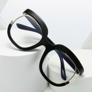 Y2K oversized black blue light glasses with gold metal accents on white pedestals