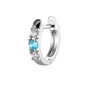 Silberner Huggie-Ohrring mit blauem Zirkon und weißen Seitensteinen auf weißem Hintergrund