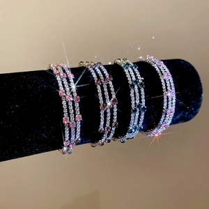 Close-up of triple-row zircon wrap bracelets in pink, purple, and green on a black stand