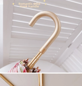 Close-up of golden J-shaped umbrella handle with colorful floral fabric detail